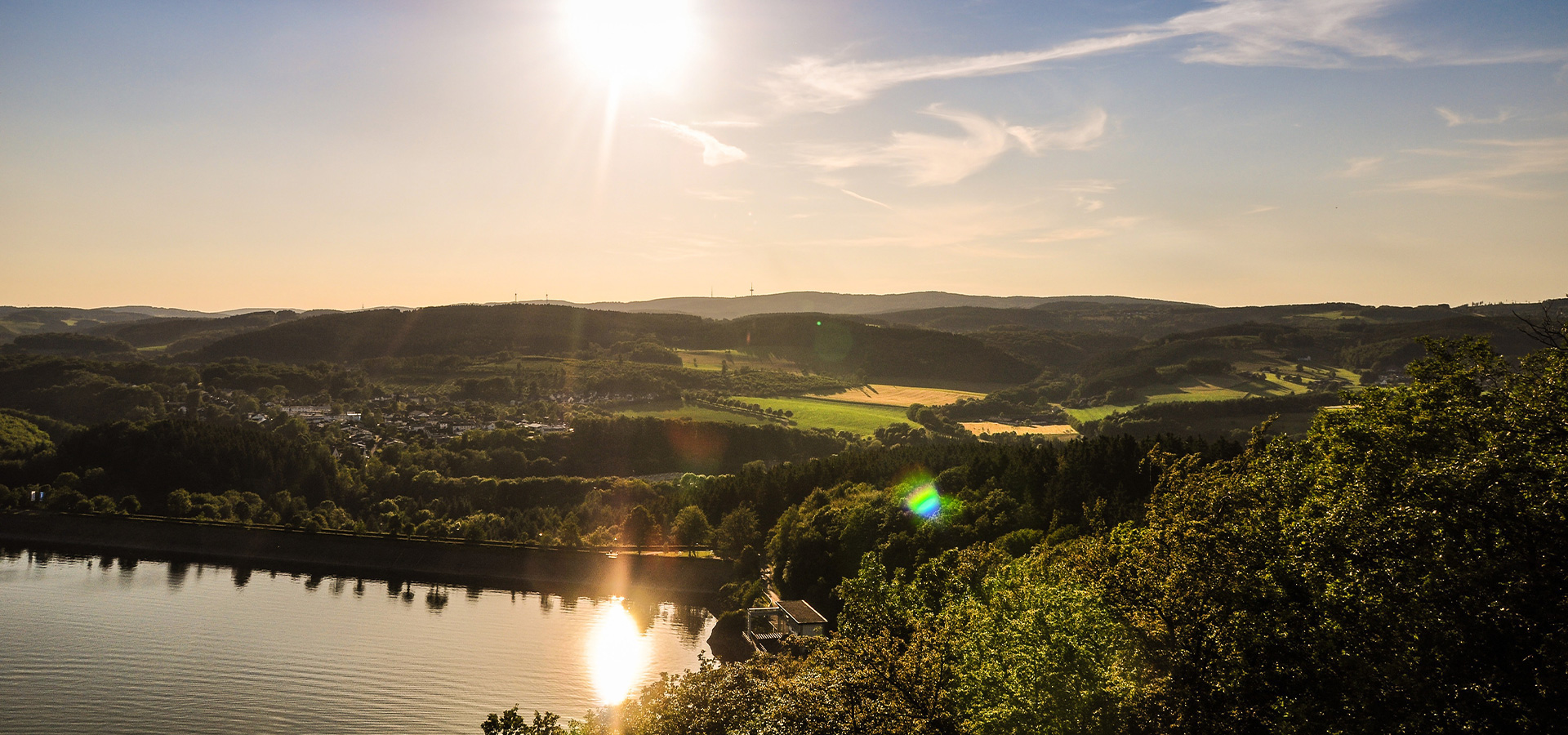 Sonnige Landschaft im Sauerland mit See, Wald und Hügeln