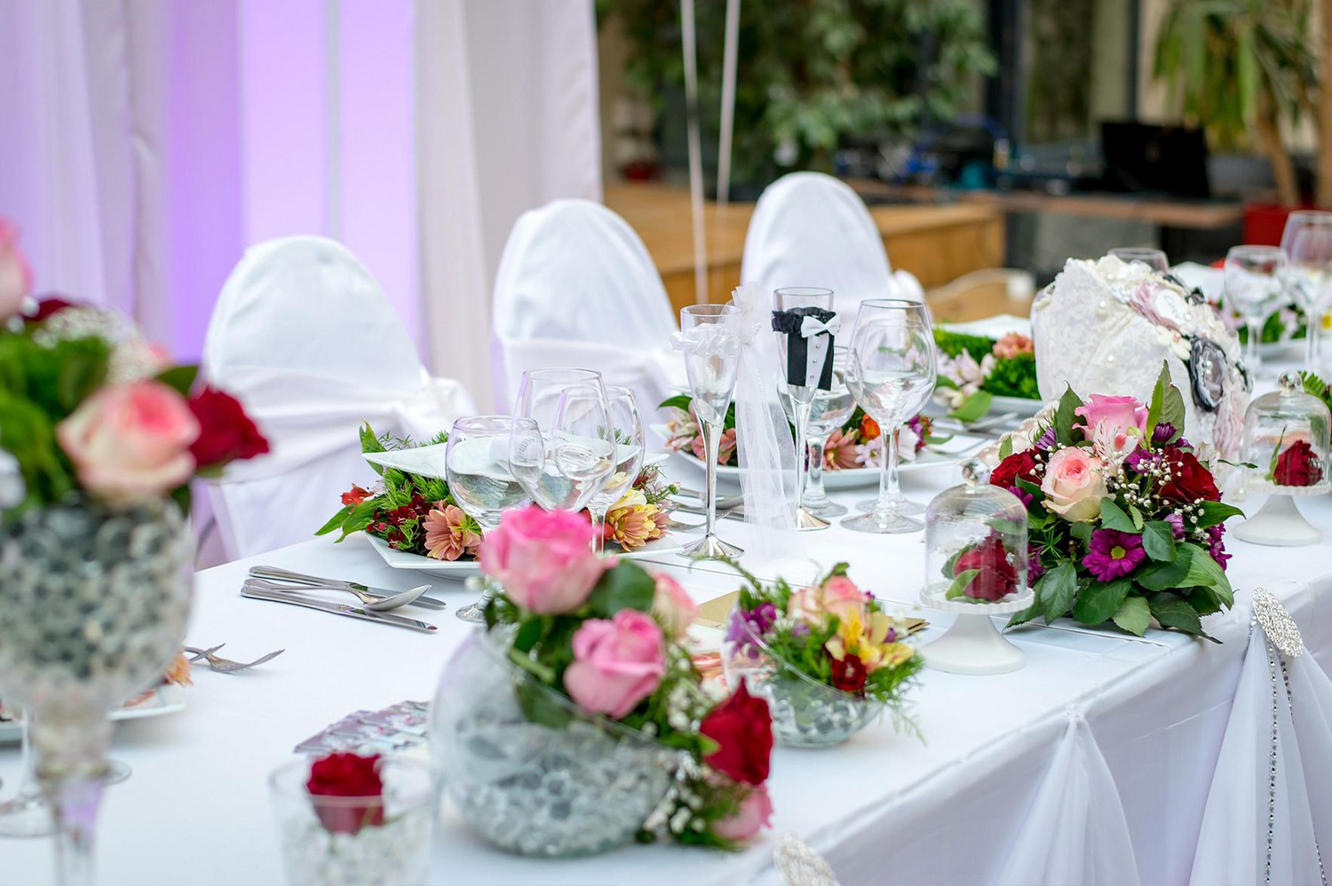 Feste-feiern Festlich gedeckter Tisch mit Blumen, Gläsern und weißen Stuhlhussen