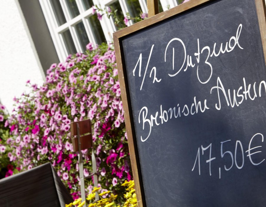 Angebotstafel im Biergarten des Haus Dumicketal mit Blumen im Hintergrund