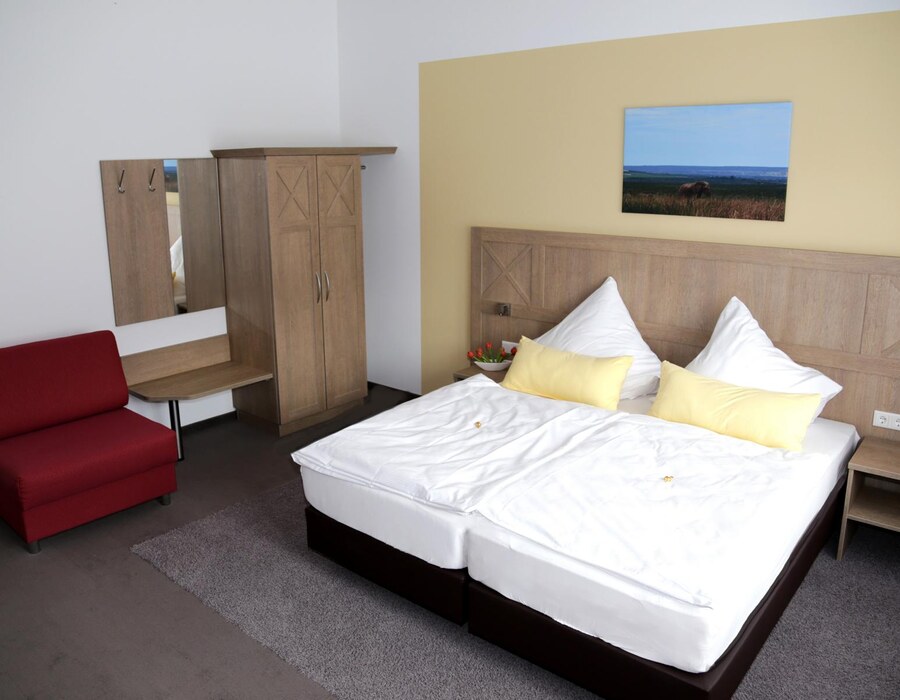 Helles Doppelzimmer mit großem Bett, Schrank, Sitzbereich und Fernseher