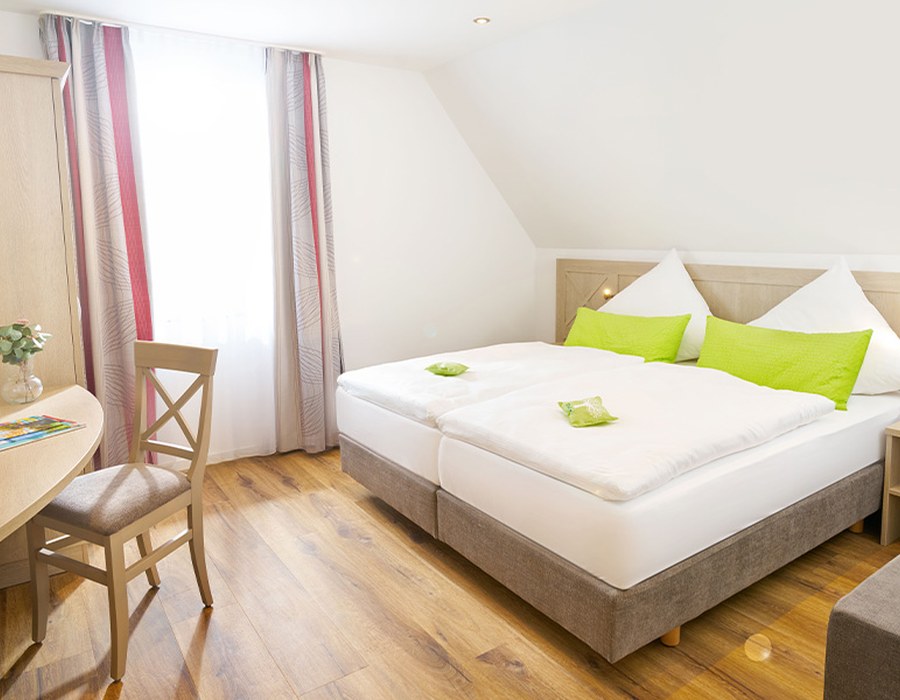 Helles Schlafzimmer im Ferien-Apartment mit Doppelbett, Stuhl und grünen Akzenten