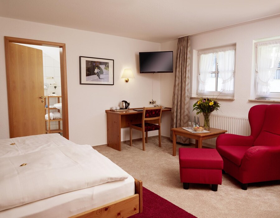 Gemütliches Gästezimmer im Haus Dumicketal mit Bett, Schreibtisch, Fernseher und rotem Sessel