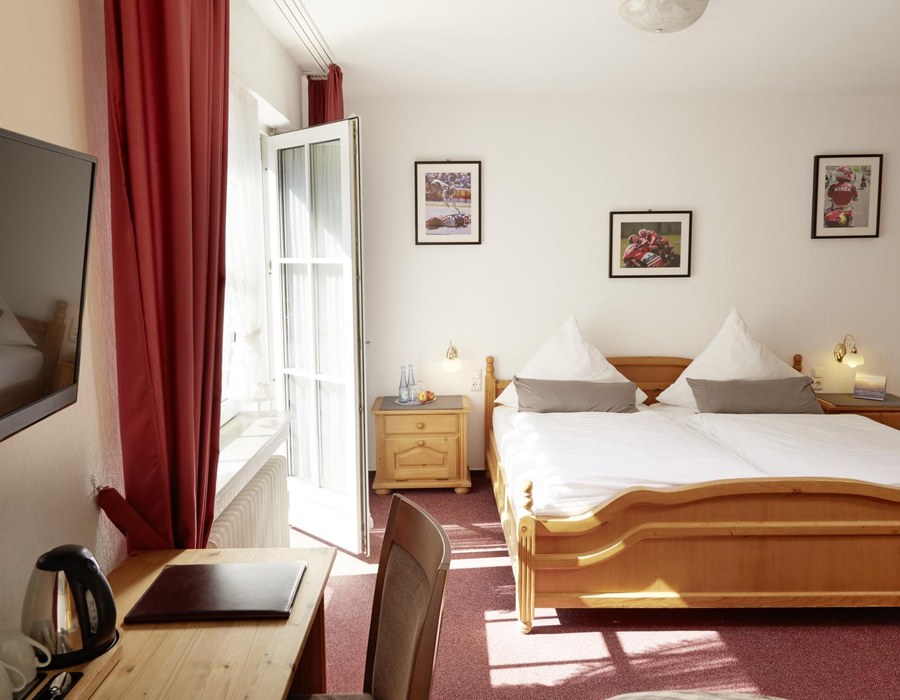 Gemütliches Gästezimmer im Landhausstil mit Doppelbett und rotem Vorhang