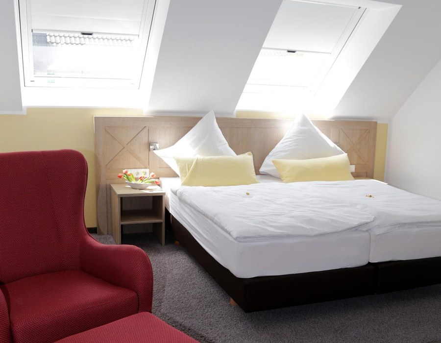 Komfortables Doppelzimmer mit großem Bett, Sesseln und Dachfenstern
