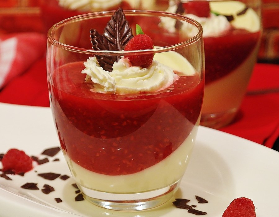 Dessert im Glas mit roter Fruchtschicht, Sahne und Schokoladendekor