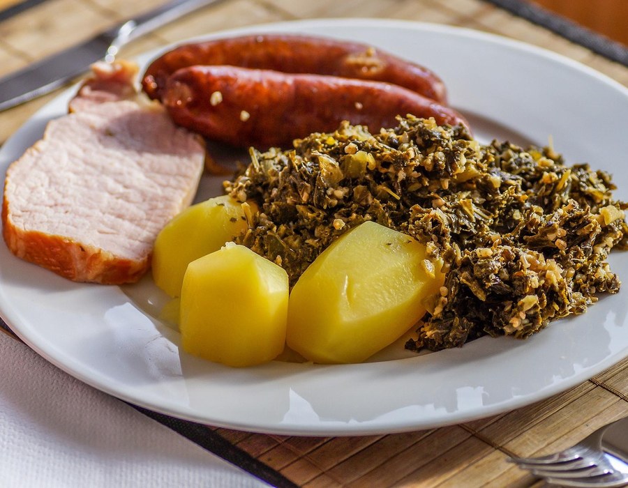 Grünkohlessen Sauerland Haus Dumicketal Grünkohlgericht mit Kassler, Mettwurst, Kartoffeln und Senf auf einem Teller