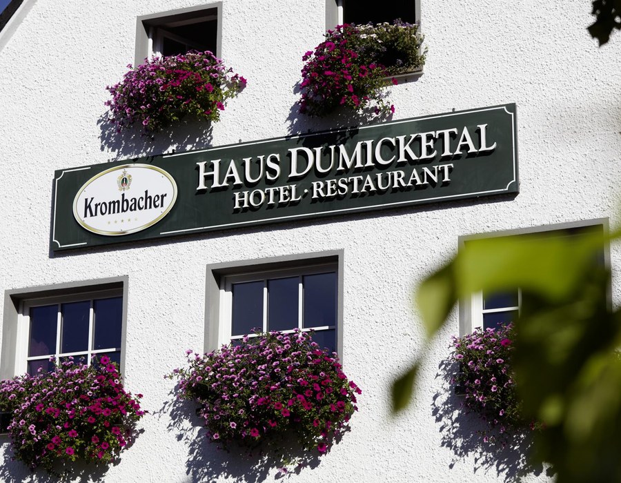 Fassade des Haus Dumicketal mit Hotelschild und blühenden Balkonkästen