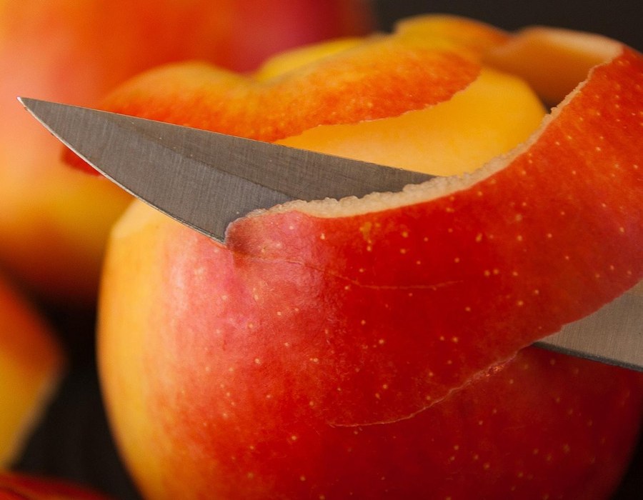Roter Apfel wird mit einem Messer geschält