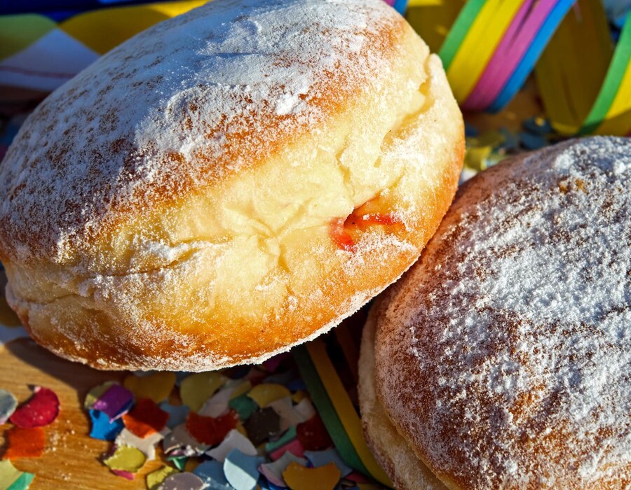 Mit Puderzucker bestäubte Berliner auf buntem Konfetti
