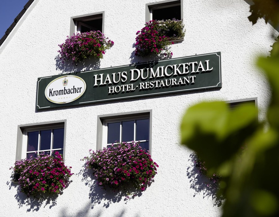 Fassade des Haus Dumicketal mit Hotelschild und blühenden Balkonkästen