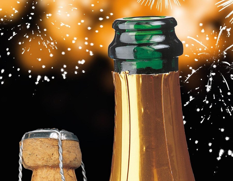 Sektflasche mit knallendem Korken zum Anstoßen an Silvester